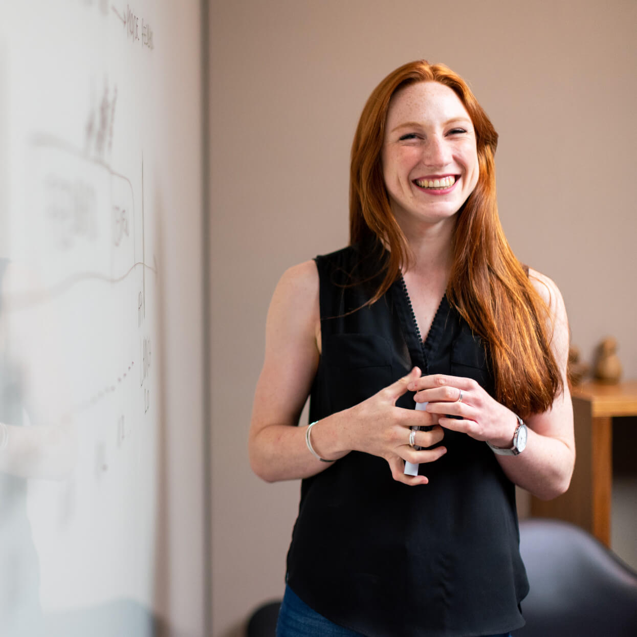 a woman is smiling in front of a white board