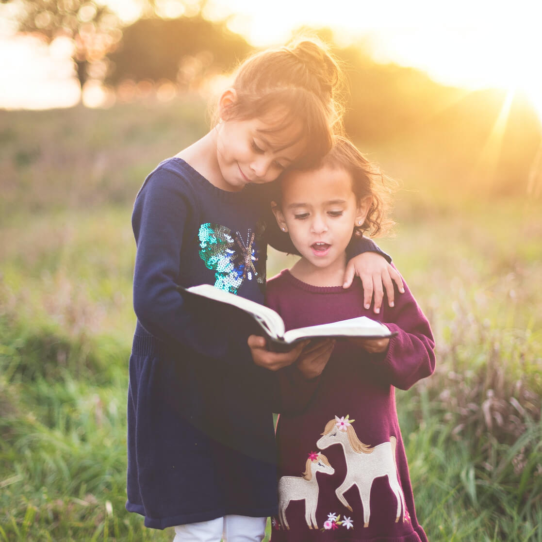 kids are reading a book in nature